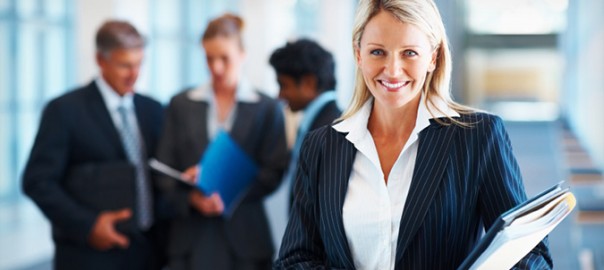 Smiling businesswoman holding folders with colleagues behind
