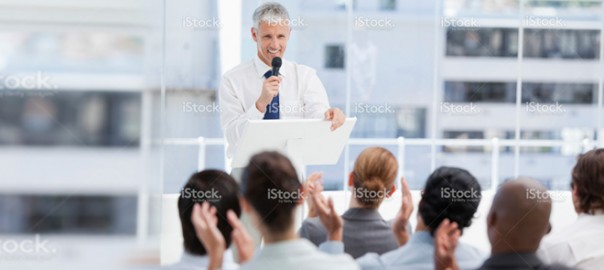 Businessman speaking at podium to applauding audience