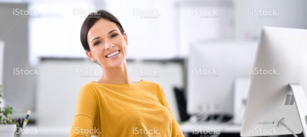 Smiling woman in yellow sweater at office computer