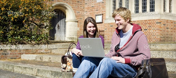 Two students on campus steps using laptop