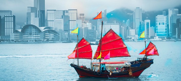 Traditional red-sailed junk boat against city skyline
