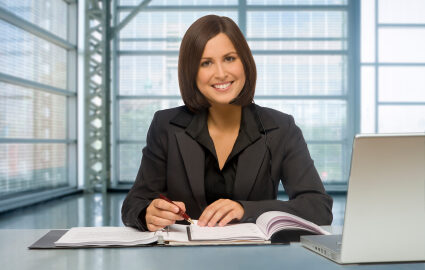 Smiling businesswoman writing at office desk