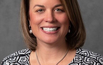 Smiling woman wearing patterned jacket and necklace