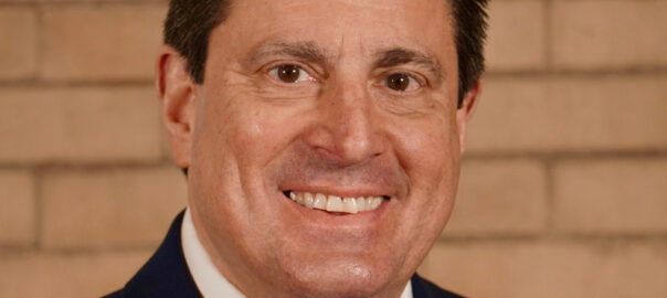 Smiling man in navy suit with purple tie